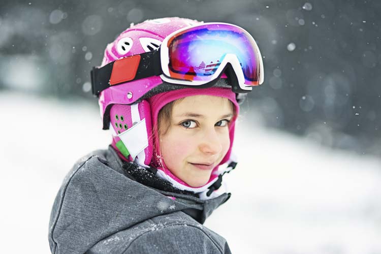 Bambina nella neve con casco da sci